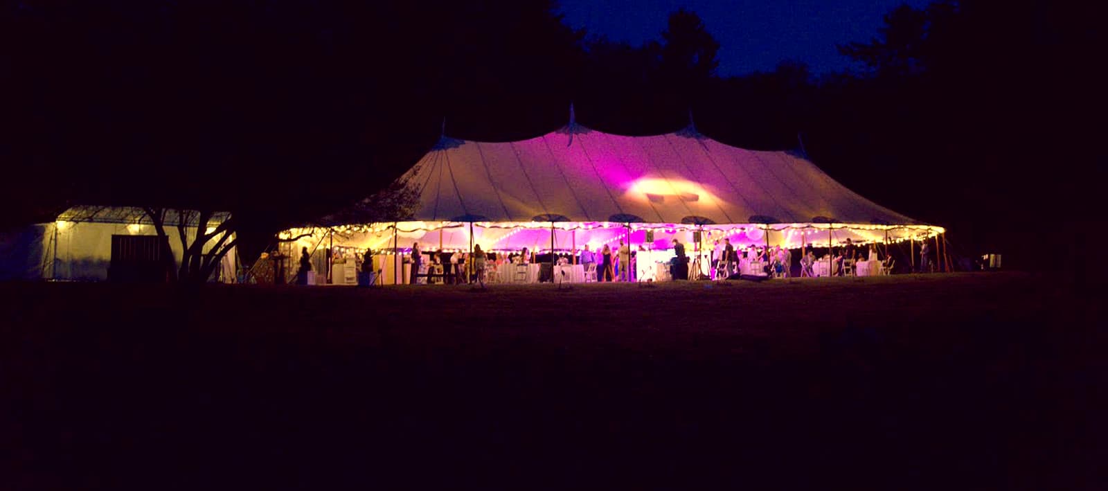 A wedding tent glowing at night, lit from inside