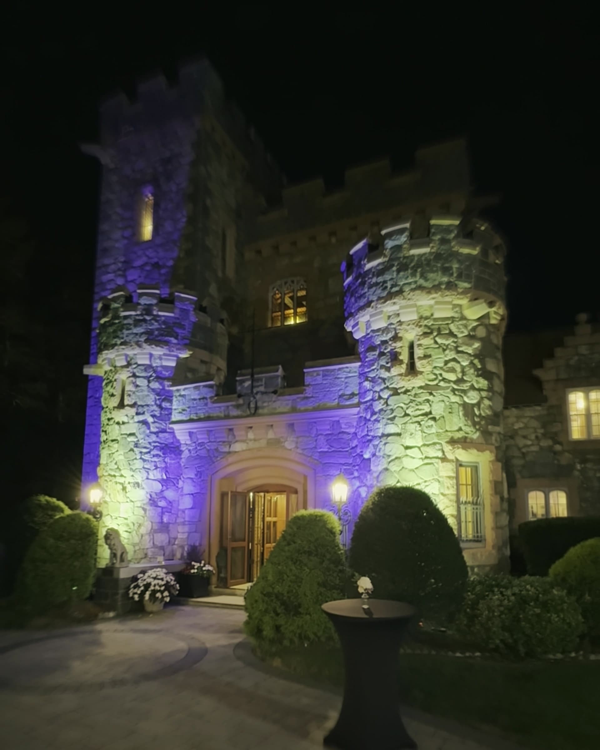 A stone castle venue washed in violet and amber uplighting at night